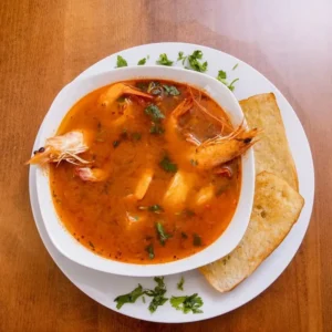 Steaming bowl of authentic Caldo de Mariscos (seafood stew) served with fresh cilantro and crusty bread at Unos Mariscos O Que in Round Rock, TX.