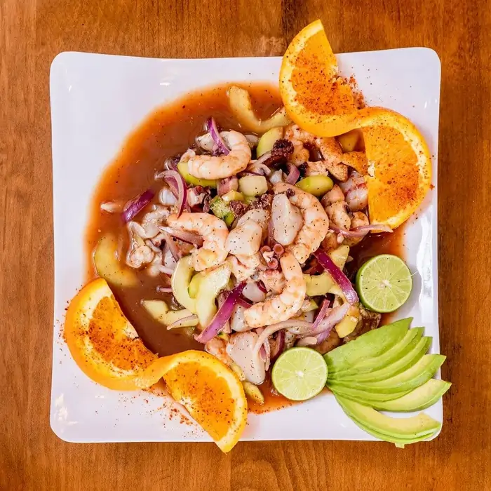 Authentic Unos Mariscos O Que Mix featuring shrimp, octopus, and scallops in a signature red sauce, garnished with avocado and orange slices in Round Rock, TX.